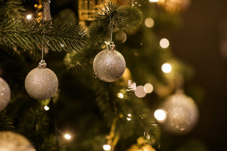 Close up view of beautiful fir branches with shiny golden bauble or ball, xmas ornaments and lights, Christmas holidays background. copyspace. Decoration on christmas tree. Festive new 2023 year.の写真素材
