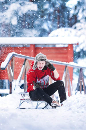 Young cheerful caucasian man is wearing worm red sweatshirt and fun winter ear hat is having fun...