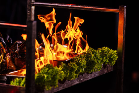 preparation vegetables or meat food in a frying pan with a flame of fire. The concept of restaurant and hotel service. Flamber or cooking over natural fire. grand cuisine.の写真素材