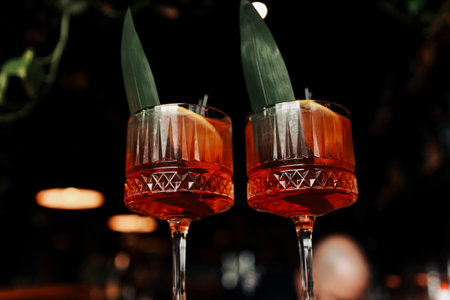 cocktail Aperol spritz in glasses. Cocktail aperol spritz decorated with fresh orange slices, ice, greens and two black straw. Typical italian beverage, aperitif made with Prosecco sparkling white wine.の写真素材