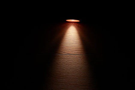 Flashlight and a beam of light in darkness. A modern led light with bright projection on dark wood table. Surface with copy space. power age. collapse of the power systemの写真素材