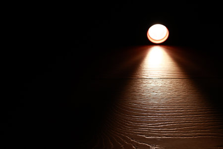 Flashlight and a beam of light in darkness. A modern led light with bright projection on dark wood table. Surface with copy space. power age. collapse of the power systemの写真素材