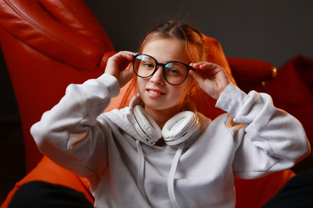 Fashion kid concept - stylish little girl child wearing a casual sweatshirt and headphones, touching...