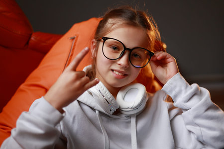 Attractive stylish little girl child wearing a casual sweatshirt and headphones, showing rock n roll...