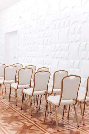 Row of festive elegantly gold metal chairs with white cloth indoors hallの写真素材