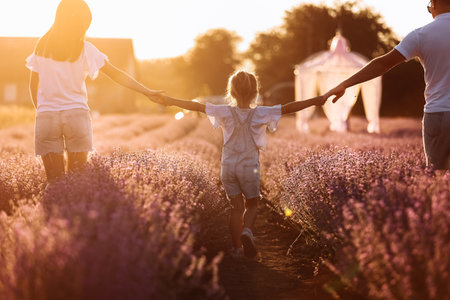 happy family day. young father, mother and child daughter are having fun together in the lavender field and looking at each other. happy couple with kid enjoy summer holiday vacation. family look.の写真素材