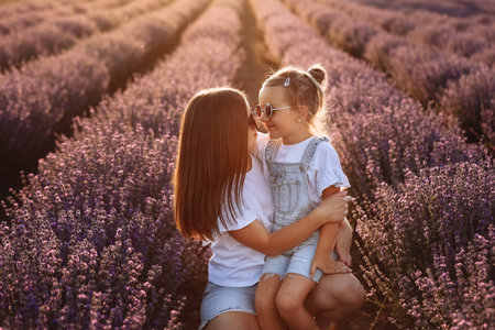 Happy family in purple lavender field. young beautiful mother and child Girl enjoy walking blooming meadow on summer day. Mom having fun with pretty daughter in nature on sunset. mother's day.の写真素材