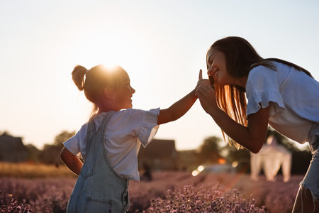 Happy family in purple lavender field. young beautiful mother and child Girl enjoy walking blooming meadow on summer day. Mom having fun with pretty daughter in nature on sunset. mother's day.の写真素材