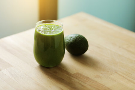 Green organic smoothie made from freshly prepared raw vegetables in a glass and whole avocado on wooden background. Vegan diet and nutrition, healthy detox, alkaline food, vegetarian concepts drinks.の写真素材