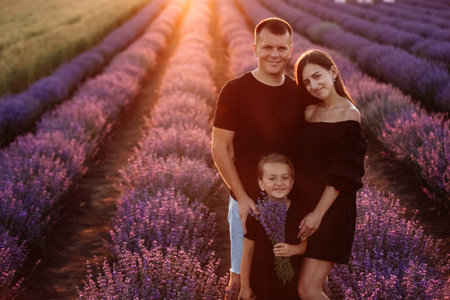 happy family day. young father, mother and child daughter are having fun together in the lavender field. happy couple with kid enjoy summer holiday vacation. family look.の写真素材