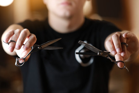 Barbershop. Unrecognizable hairdresser is holding two types of scissors. barber professional tools. Male haircut, fashion. Hair salon, hair cut and shaving background. small business. selective focus.の写真素材