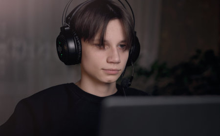 Young gamer man in glasses with screen reflection and headphones streaming live action game while...