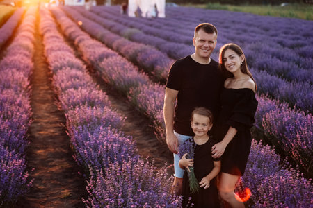 happy family day. young father, mother and child daughter are having fun together in the lavender field. happy couple with kid enjoy summer holiday vacation. family look.の写真素材