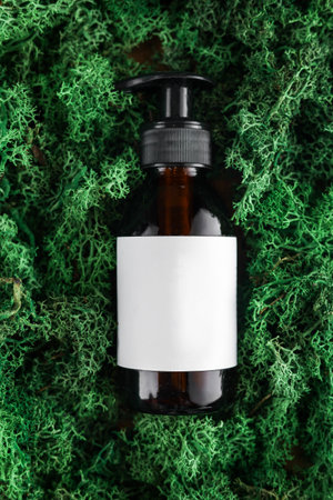 Amber dark glass bottle with dispenser of cosmetic product on green moss background, mock up. Organic body treatment, skin care, spa concept. Biophilia design. Vegan eco bio friendly cosmetologyの写真素材