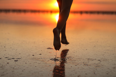 Active summer travel holiday. Cropped photo of legs silhouette of energy little child girl, boy having fun runs and plays on beach at sunset. Youth, lifestyle and happiness concept. children's day.の写真素材