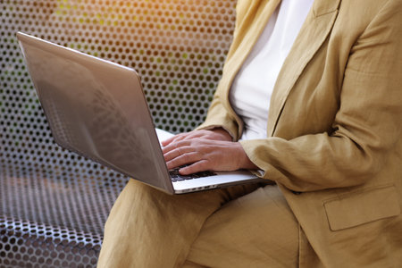 Work life balance. Unrecognizable adult woman works, types on laptop on bench outdoors. Freelance social distance work, e-learning, connection, creative professional, business, meeting online concept.の写真素材