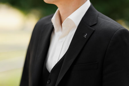 Cropped front view shot of man wearing white shirt with up unbuttoned button, waistcoat and classic black suit outdoors. Grooms morning preparation. Informal business meetingの写真素材