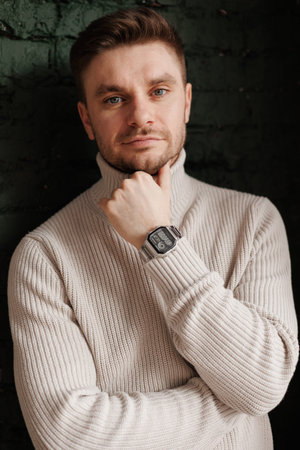 Young handsome bearded man wears casual warm knitted sweater on brick wall background with happy face smiling with crossed arms looks at the camera. Positive people sincere emotions lifestyle concept.の写真素材