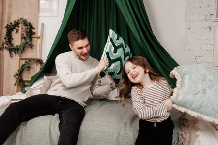 Pillow fight, happy young father and child daughter playing, having fun laughing for funny games,...