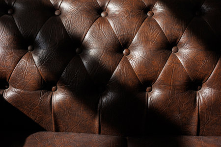Detail of luxury quilted brown leather sofa upholstery with buttons. Furniture design. Natural leather with rhombic stitching. Elegant classic decor interior texture and royal vintage material.の写真素材
