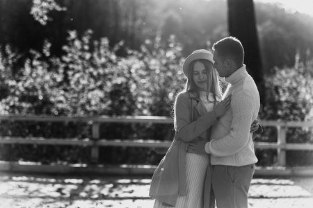 Young stylish lovers couple are hugging and kissing in the autumn park. Lovely romantic moment between man and woman in love, looking to each others. happy family. Love, youth, happiness conceptの写真素材