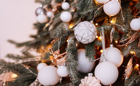 Close up of beautiful fir branches with shiny golden, silver and white baubles or balls, xmas...