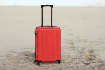 Vacation and tourism concept. Red suitcase on sandbeach on the sea ocean backdrop. Luggage for travel abroad weekend getaway. Last minute trips, hot toursの写真素材