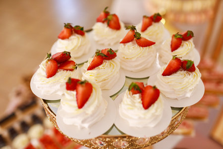 Delicious mini Pavlova meringue cakes with fresh strawberry on gold festive tray.の写真素材
