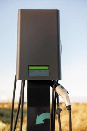 Power supply with cables for charging of electric car on parking lot outdoors. Charging battery at EV charging station. Green energy, zero emission and eco friendly car conceptの写真素材