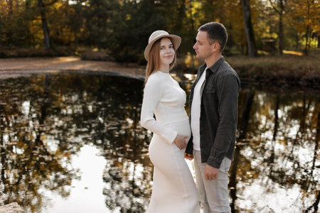 Family day. Stylish marriage pregnant couple waiting for baby. Man is hugging and touching woman belly outdoors. World IVF Day. Pregnancy, parenthood, motherhood, love, family conceptの写真素材