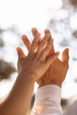 Close up loving couple hold hands showing engagement ring with diamond on ring finger on nature...
