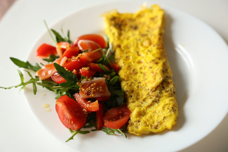 Healthy breakfast with omelette and fresh salad with cherry tomatoes and arugula, dressed with...