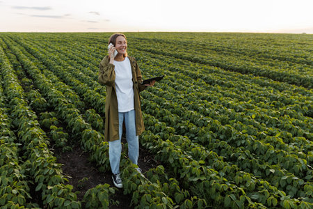 Modern agribusiness. Happy female farmer with digital tablet, talks on smartphone after examiner and...