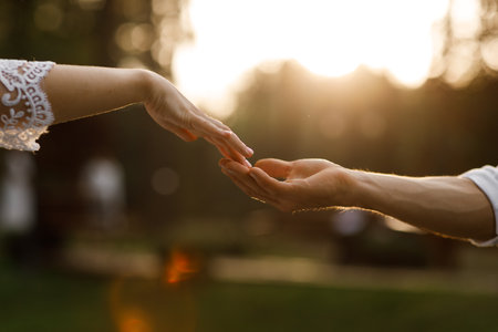 hands of romantic couple a close-up. hands men and women symbol love teamwork sunlight happy family together. silhouette hands support stroking each other. dating, romantic atmosphere.の写真素材