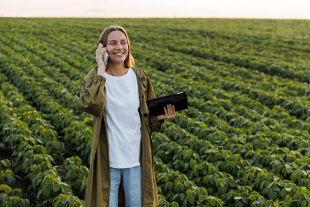 Modern agribusiness. Happy female farmer with digital tablet, talks on smartphone after examiner and...