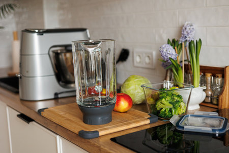 Healthy ingredients for detox smoothie drink and lifestyle diet. Glass blender bowl, apple, banana, broccoli, parsley on table top at modern home kitchen. Fresh fruits, vegetables and greensの写真素材