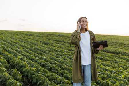 Modern agribusiness. Happy female farmer with digital tablet, talks on smartphone after examiner and...