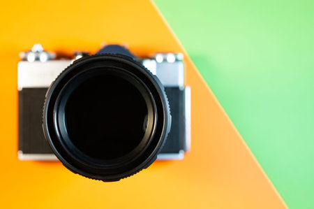 Film SLR photo camera with telephoto lens on orange and green backgroundの写真素材