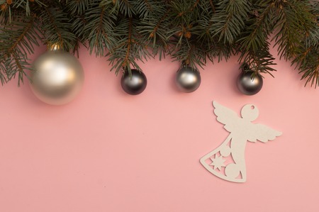 Pearl Christmas balls and white figure of angel on the pink background with pine tree branchesの写真素材