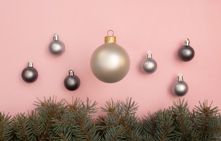 Multiple pearl Christmas balls on the pink background with pine tree branches in the bottomの写真素材