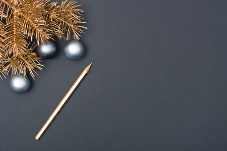 Golden Christmas tree branches decorated with silver baubles and golden pencil on the black backgroundの写真素材