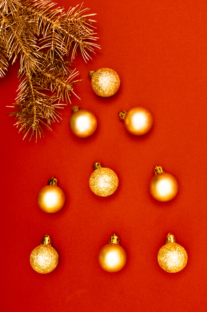 Golden Christmas tree branches are crying with golden baubles on the red backgroundの写真素材