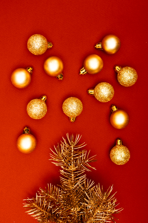 Golden Christmas tree branches are flooding like fountain with golden baubles on the red backgroundの写真素材