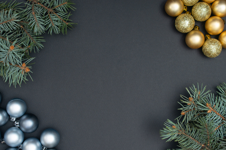 Multiple Christmas silver and gold baubles and Christmas tree branches in the corners of the black backgroundの写真素材