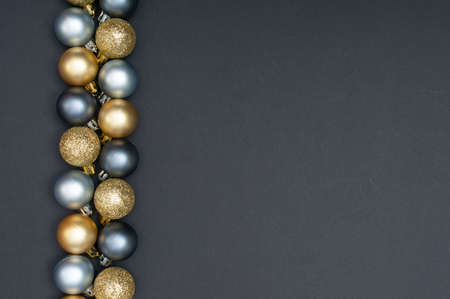 Multiple Christmas silver and gold baubles aligned on the left of the black backgroundの写真素材
