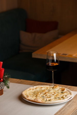Four cheese pizza quattro formaggi with glass of wine on dark background.の写真素材