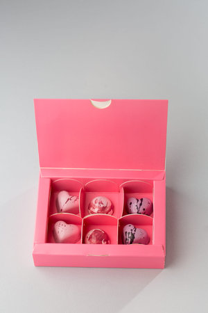Luxury handmade chocolate candy in pink box isolated on dark background. Exclusive handcrafted...