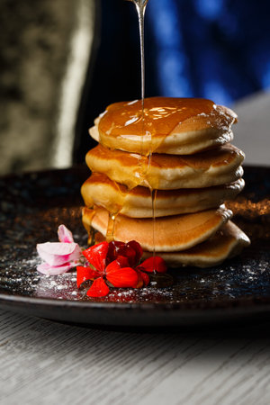 American pancakes with berries and maple syrup on black plate isolated with coffee. cafe menu.