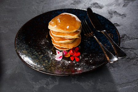 American pancakes with berries and maple syrup on black plate isolated with coffee. cafe menu.