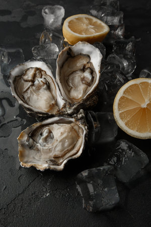 Fresh Oysters close-up on dark background, served table with oysters, lemon and ice. Healthy sea food. gourmet food. top viewの写真素材